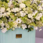 گل های سبز و سفید در باکس گل سبز پاستلی روشن می‌درخشد.